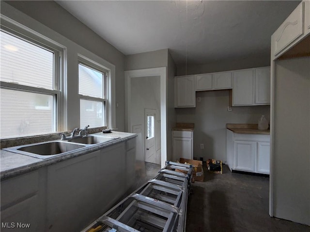 15002 Kingsford Ave, Cleveland, OH 44128 - kitchen featuring a sink, white cabinets, and concrete floors