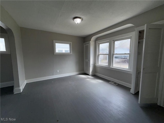 15002 Kingsford Ave, Cleveland, OH 44128 - unfurnished bedroom featuring arched walkways, baseboards, and dark wood-style flooring