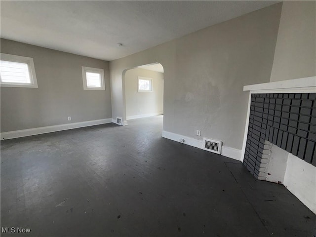 15002 Kingsford Ave, Cleveland, OH 44128 - unfurnished living room with arched walkways, a brick fireplace, and baseboards