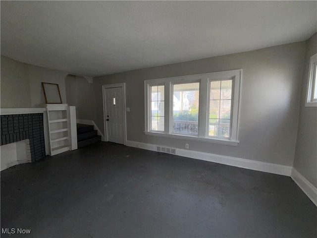 15002 Kingsford Ave, Cleveland, OH 44128 - unfurnished living room featuring concrete flooring, a fireplace, healthy amount of natural light, and baseboards