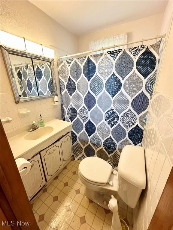 808 Gilbert Ave, Follansbee, WV 26037 - full bathroom with toilet, vanity, curtained shower, tile walls, and tile patterned floors