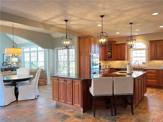 4679 Paxton Rd, Copley, OH 44321 - kitchen featuring a chandelier, brown cabinets, backsplash, stainless steel double oven, and arched walkways