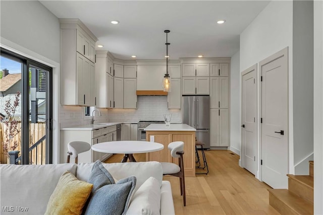 1904-2 E 123rd St, Cleveland, OH 44106 - kitchen with high end appliances, a kitchen island, light countertops, light wood-style floors, and tasteful backsplash