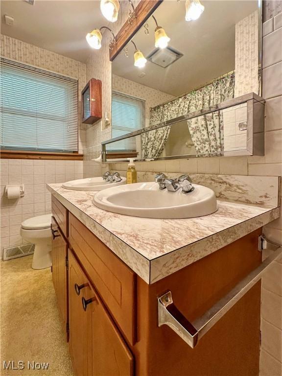 195 Fairlawn Ave, Niles, OH 44446 - full bath with wallpapered walls, tile walls, vanity, toilet, and a shower