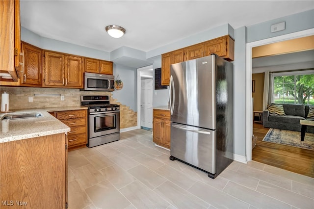 1167 Croyden Rd, Lyndhurst, OH 44124 - kitchen with appliances with stainless steel finishes, baseboards, brown cabinets, backsplash, and light stone counters