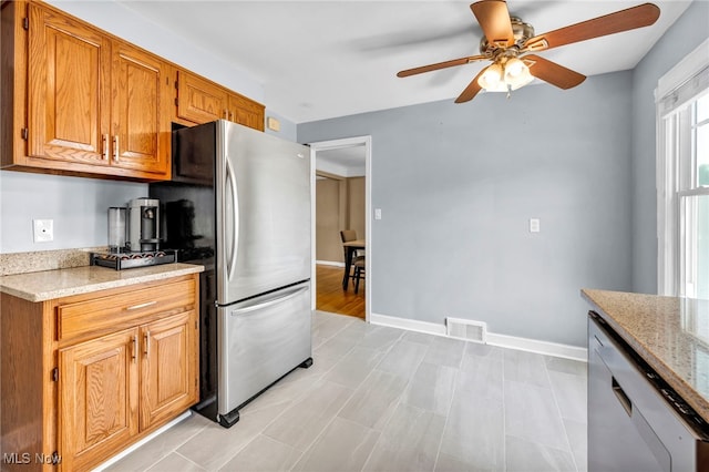 1167 Croyden Rd, Lyndhurst, OH 44124 - kitchen featuring stainless steel appliances, a ceiling fan, light stone countertops, brown cabinetry, and baseboards