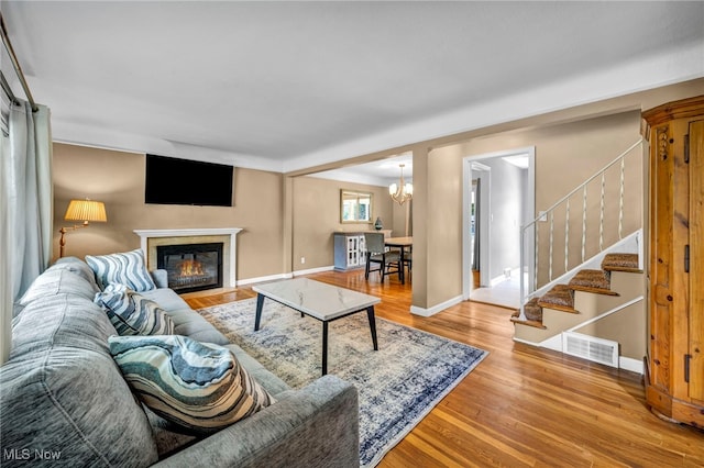 1167 Croyden Rd, Lyndhurst, OH 44124 - living room with wood finished floors, stairway, a fireplace with flush hearth, a chandelier, and baseboards