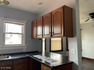200 Stewart Ave NW, Massillon, OH 44646 - kitchen with dark countertops, ceiling fan, a desk, a sink, and a textured ceiling