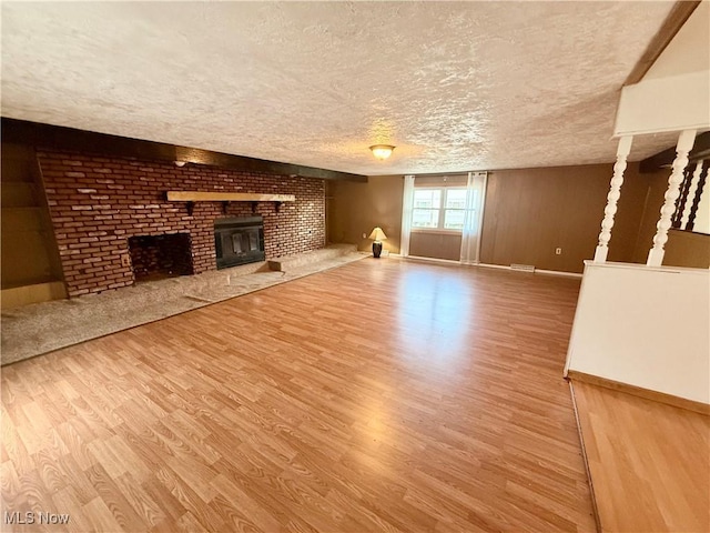 47 Walker Manor Cir, Colliers, WV 26035 - unfurnished living room featuring wood finished floors, a textured ceiling, and a brick fireplace