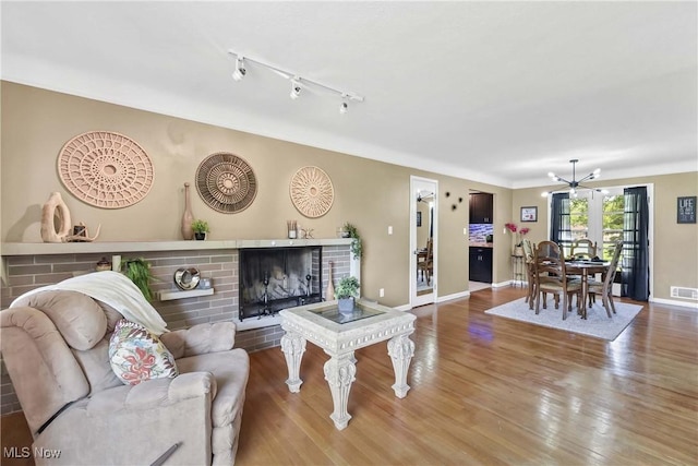 321 Justo Ln, Seven Hills, OH 44131 - living area featuring a brick fireplace, wood finished floors, baseboards, a chandelier, and rail lighting