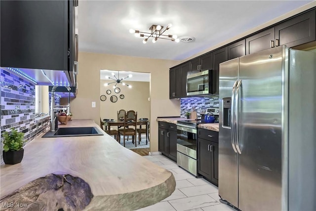 321 Justo Ln, Seven Hills, OH 44131 - kitchen with appliances with stainless steel finishes, a chandelier, tasteful backsplash, light countertops, and dark cabinets