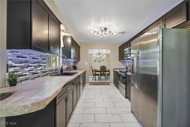 321 Justo Ln, Seven Hills, OH 44131 - kitchen with appliances with stainless steel finishes, a sink, a chandelier, and tasteful backsplash