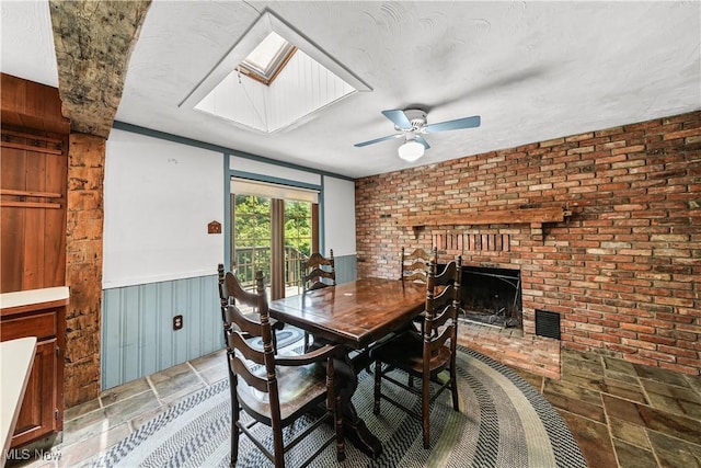 11828 Sheldon Rd, Mantua, OH 44255 - dining space featuring a skylight, a brick fireplace, a ceiling fan, stone finish floors, and brick wall