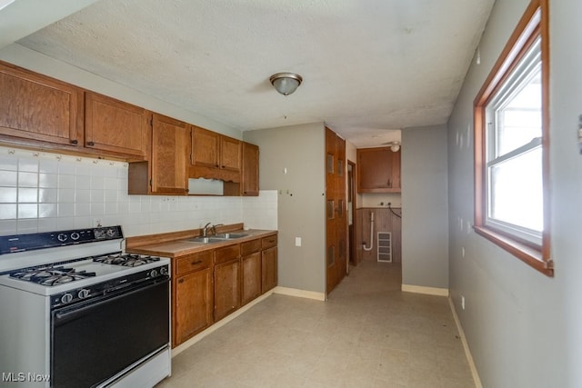 24120 Sherborne Rd, Bedford Heights, OH 44146 - kitchen featuring range with gas cooktop, a sink, brown cabinetry, decorative backsplash, and light flooring