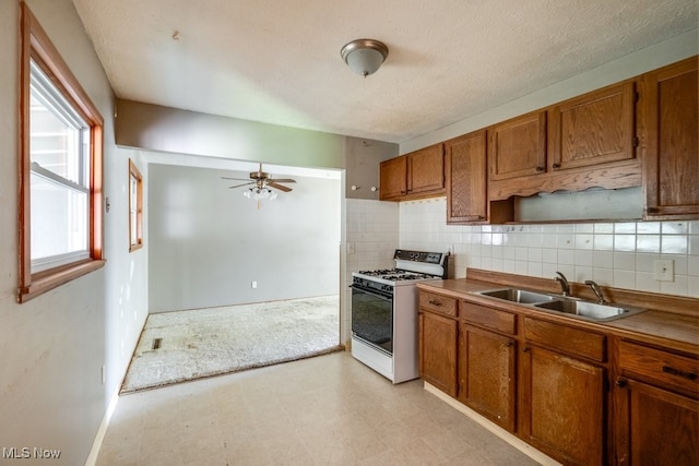24120 Sherborne Rd, Bedford Heights, OH 44146 - kitchen with white range with gas stovetop, a sink, brown cabinets, and light floors