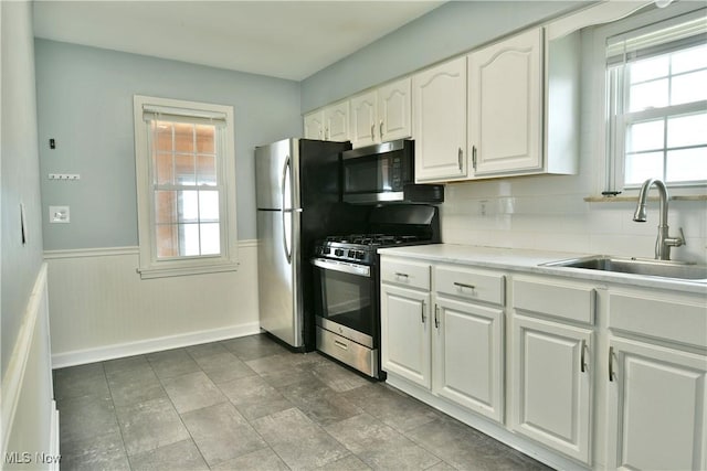 859 Gary Ave, Girard, OH 44420 - kitchen featuring appliances with stainless steel finishes, a sink, white cabinets, wainscoting, and light countertops
