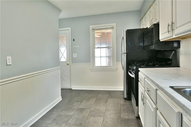 859 Gary Ave, Girard, OH 44420 - kitchen featuring gas stove, a wainscoted wall, white cabinets, tasteful backsplash, and light stone countertops