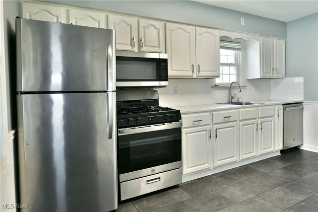 859 Gary Ave, Girard, OH 44420 - kitchen with stainless steel appliances, a sink, white cabinets, light countertops, and backsplash