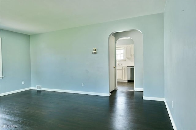 859 Gary Ave, Girard, OH 44420 - unfurnished room with dark wood-style floors, baseboards, arched walkways, and a sink