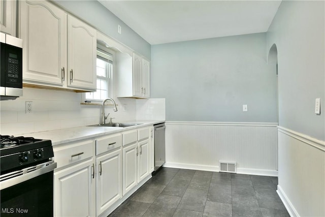 859 Gary Ave, Girard, OH 44420 - kitchen featuring a sink, stainless steel dishwasher, a wainscoted wall, white cabinetry, and black range with gas cooktop