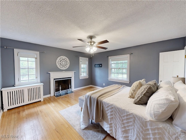 18515 Lomond Blvd, Shaker Heights, OH 44122 - bedroom featuring radiator, a textured ceiling, hardwood / wood-style flooring, baseboards, and a fireplace with flush hearth
