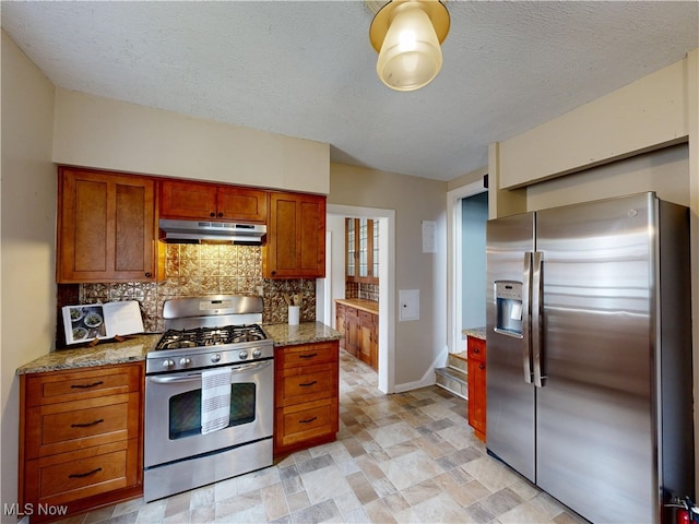 18515 Lomond Blvd, Shaker Heights, OH 44122 - kitchen with appliances with stainless steel finishes, under cabinet range hood, tasteful backsplash, brown cabinetry, and light stone counters