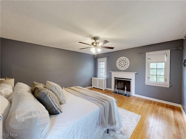18515 Lomond Blvd, Shaker Heights, OH 44122 - bedroom featuring radiator heating unit, multiple windows, hardwood / wood-style floors, baseboards, and a textured ceiling