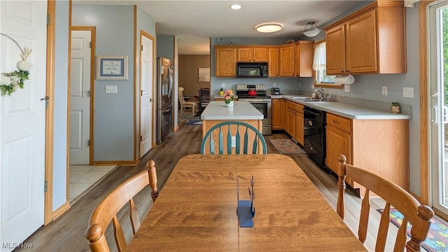 813 Buckeye Ln, Sandusky, OH 44870 - kitchen featuring black appliances, a sink, light countertops, a kitchen island, and wood finished floors
