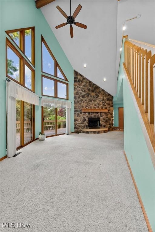 6791 Cedar Ridge Trl, Clinton, OH 44216 - unfurnished living room featuring high vaulted ceiling, carpet flooring, a ceiling fan, beamed ceiling, and a fireplace