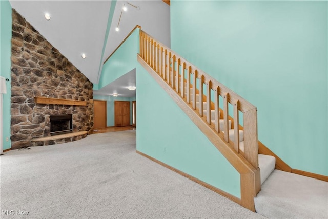 6791 Cedar Ridge Trl, Clinton, OH 44216 - staircase featuring carpet flooring, high vaulted ceiling, baseboards, and a stone fireplace
