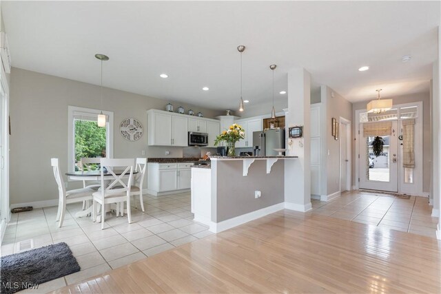 5325 S Island Dr NW, Canton, OH 44718 - kitchen featuring stainless steel appliances, baseboards, a breakfast bar area, white cabinetry, and hanging light fixtures