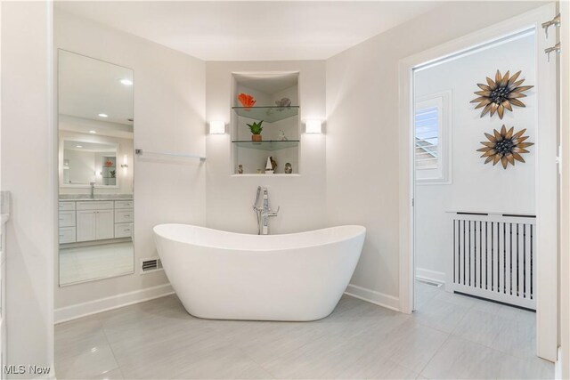 5325 S Island Dr NW, Canton, OH 44718 - bathroom with radiator heating unit, a freestanding tub, vanity, baseboards, and recessed lighting