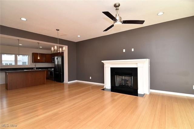 1261 W 74, Cleveland, OH 44102 - unfurnished living room with light wood-style flooring, a ceiling fan, a fireplace with flush hearth, a sink, and recessed lighting