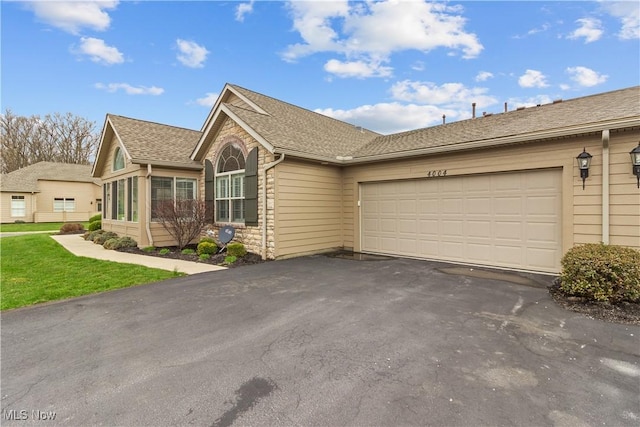 4004 Coventry Ln, Huron, OH 44839 - ranch-style house featuring asphalt driveway, a garage, stone siding, and a shingled roof