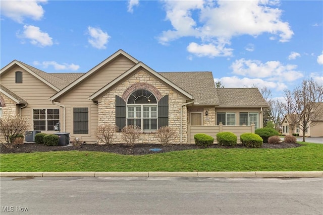 4004 Coventry Ln, Huron, OH 44839 - ranch-style home featuring stone siding, a front lawn, roof with shingles, and central air condition unit
