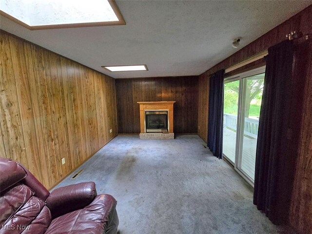 3212 Foxmoor St NE, Hartville, OH 44632 - unfurnished living room featuring wooden walls, a glass covered fireplace, carpet, and a textured ceiling
