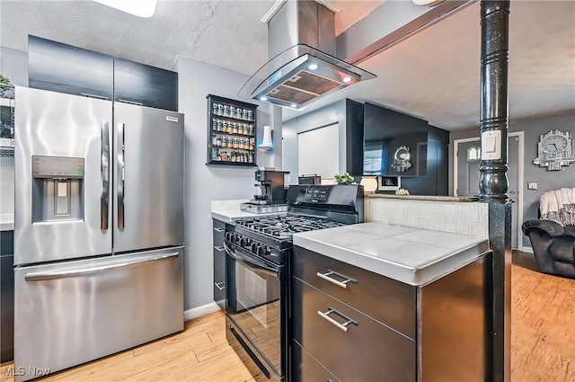 245 N Rd, Niles, OH 44446 - kitchen with stainless steel fridge, black range with gas cooktop, light wood finished floors, wall chimney range hood, and light countertops