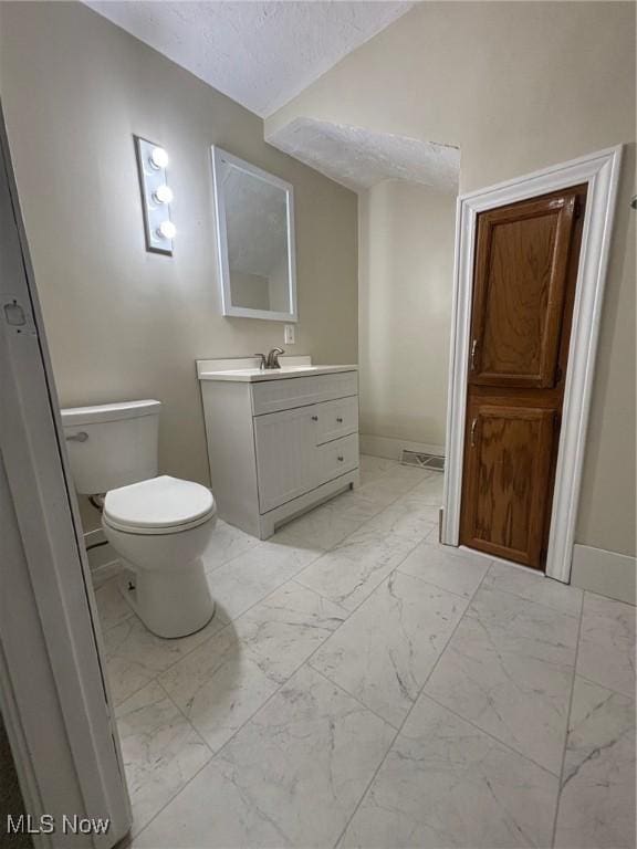 4721 Ardmore Ave, Cleveland, OH 44144 - bathroom with vanity, marble look tile flooring, toilet, vaulted ceiling, and baseboards
