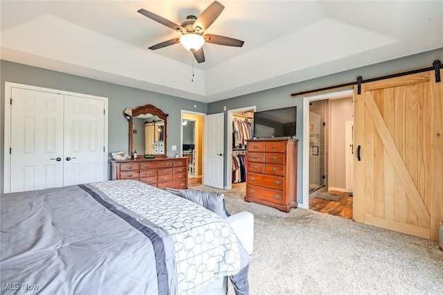 8921 Auburn Rd, Chardon, OH 44024 - carpeted bedroom featuring a barn door, a tray ceiling, ceiling fan, a closet, and a walk in closet