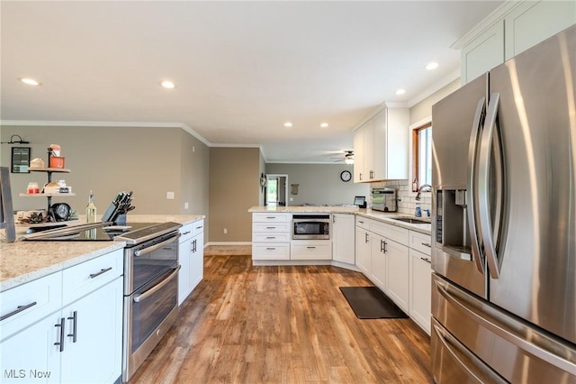 8921 Auburn Rd, Chardon, OH 44024 - kitchen featuring appliances with stainless steel finishes, a peninsula, light wood-style flooring, ornamental molding, and recessed lighting