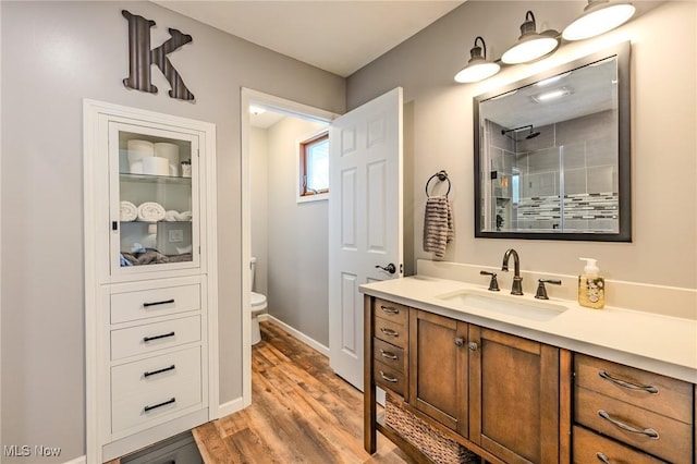 8921 Auburn Rd, Chardon, OH 44024 - bathroom featuring vanity, tiled shower, toilet, wood finished floors, and baseboards