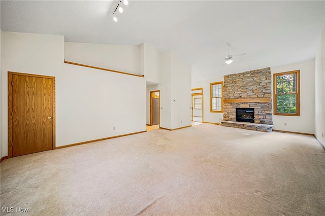 7410 Fieldstone Ave, Conneaut, OH 44030 - unfurnished living room with ceiling fan, carpet, a stone fireplace, baseboards, and high vaulted ceiling