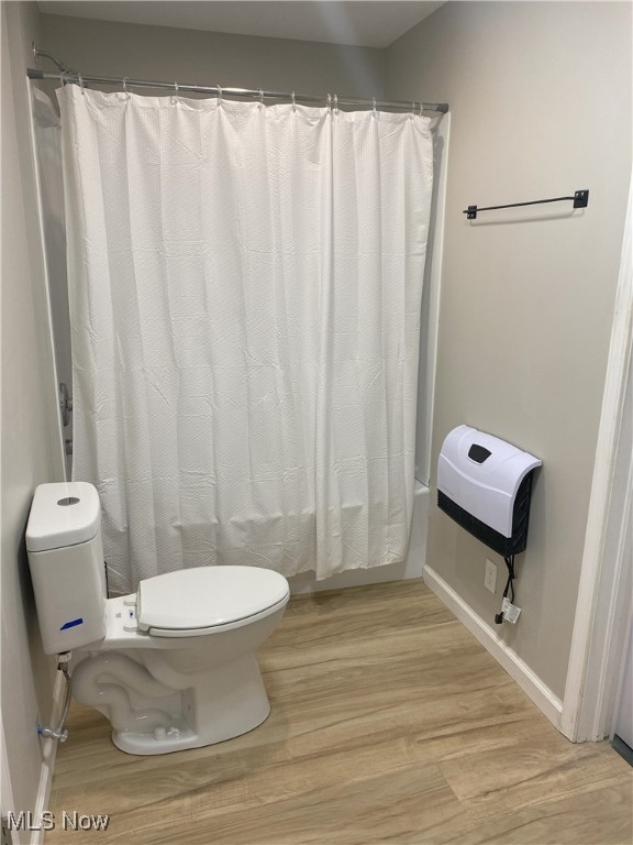 4244 Hensel Dr SW, Carrollton, OH 44615 - bathroom with toilet, wood finished floors, shower / tub combo with curtain, and baseboards