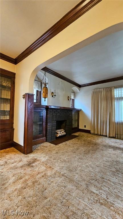 10612 Linnet Ave, Cleveland, OH 44111 - unfurnished living room featuring crown molding, a brick fireplace, baseboards, carpet, and arched walkways