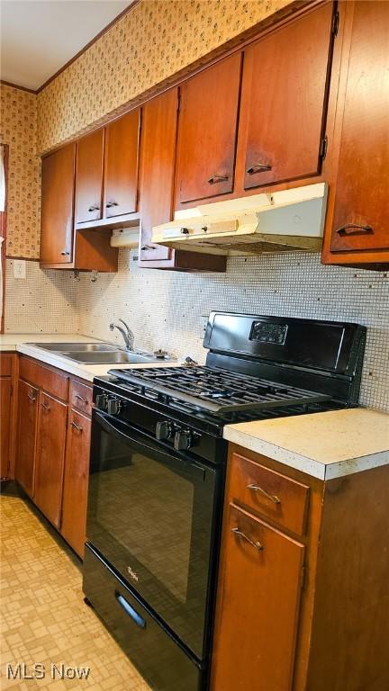10612 Linnet Ave, Cleveland, OH 44111 - kitchen with black gas range, under cabinet range hood, a sink, light countertops, and decorative backsplash
