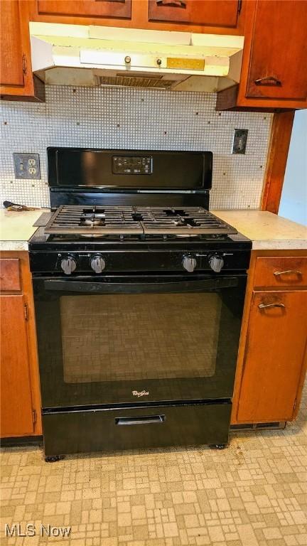 10612 Linnet Ave, Cleveland, OH 44111 - kitchen with black range with gas stovetop, light countertops, under cabinet range hood, and tasteful backsplash