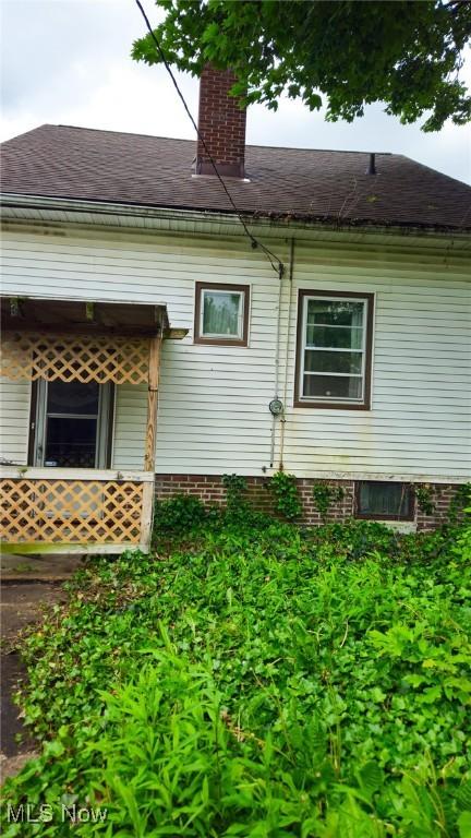 10612 Linnet Ave, Cleveland, OH 44111 - view of home's exterior featuring a chimney and a shingled roof