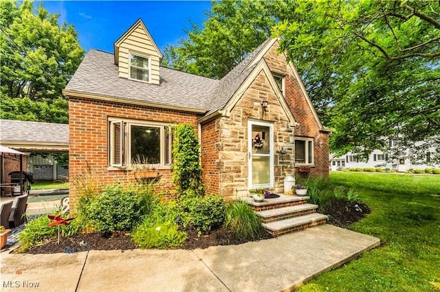 459 Lloyd Rd, Euclid, OH 44132 - tudor-style house with a front lawn, roof with shingles, brick siding, and stone siding