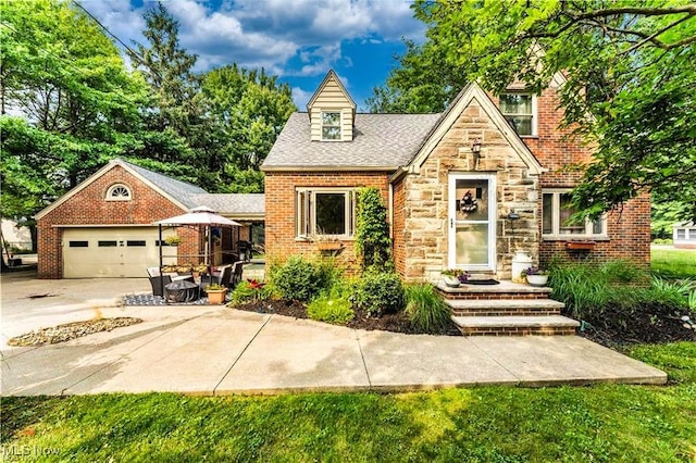 459 Lloyd Rd, Euclid, OH 44132 - tudor-style house with stone siding, an attached garage, driveway, brick siding, and a shingled roof
