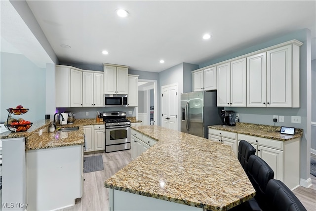 3425 Eryn Pl, Hudson, OH 44236 - kitchen featuring stainless steel appliances, a sink, a kitchen island, light wood finished floors, and light stone countertops